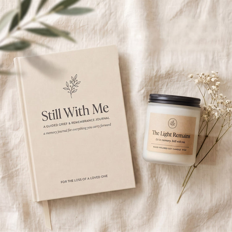 The Still With Me journal beside The Light Remains soy candle and baby's breath on warm linen