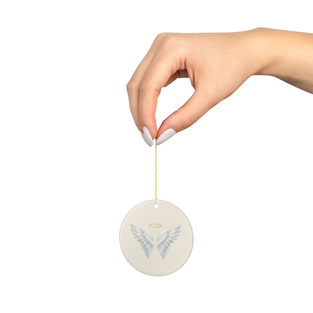 Angel wings memorial ornament hanging from a hand on its gold string