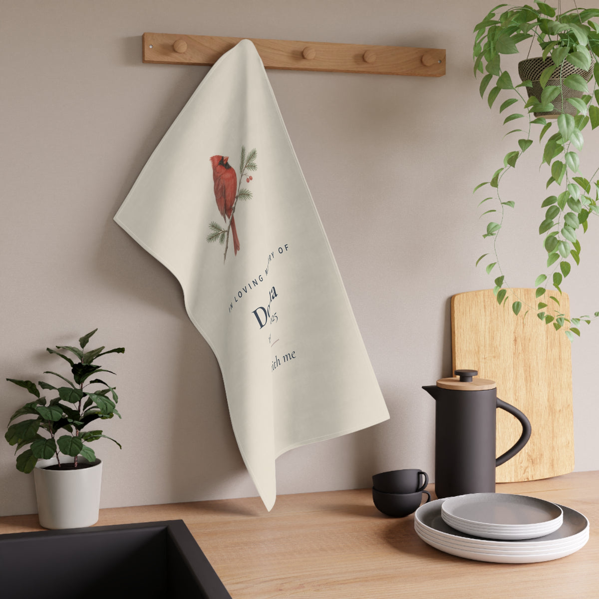 Cardinal memorial tea towel hanging from a wooden hook in a kitchen
