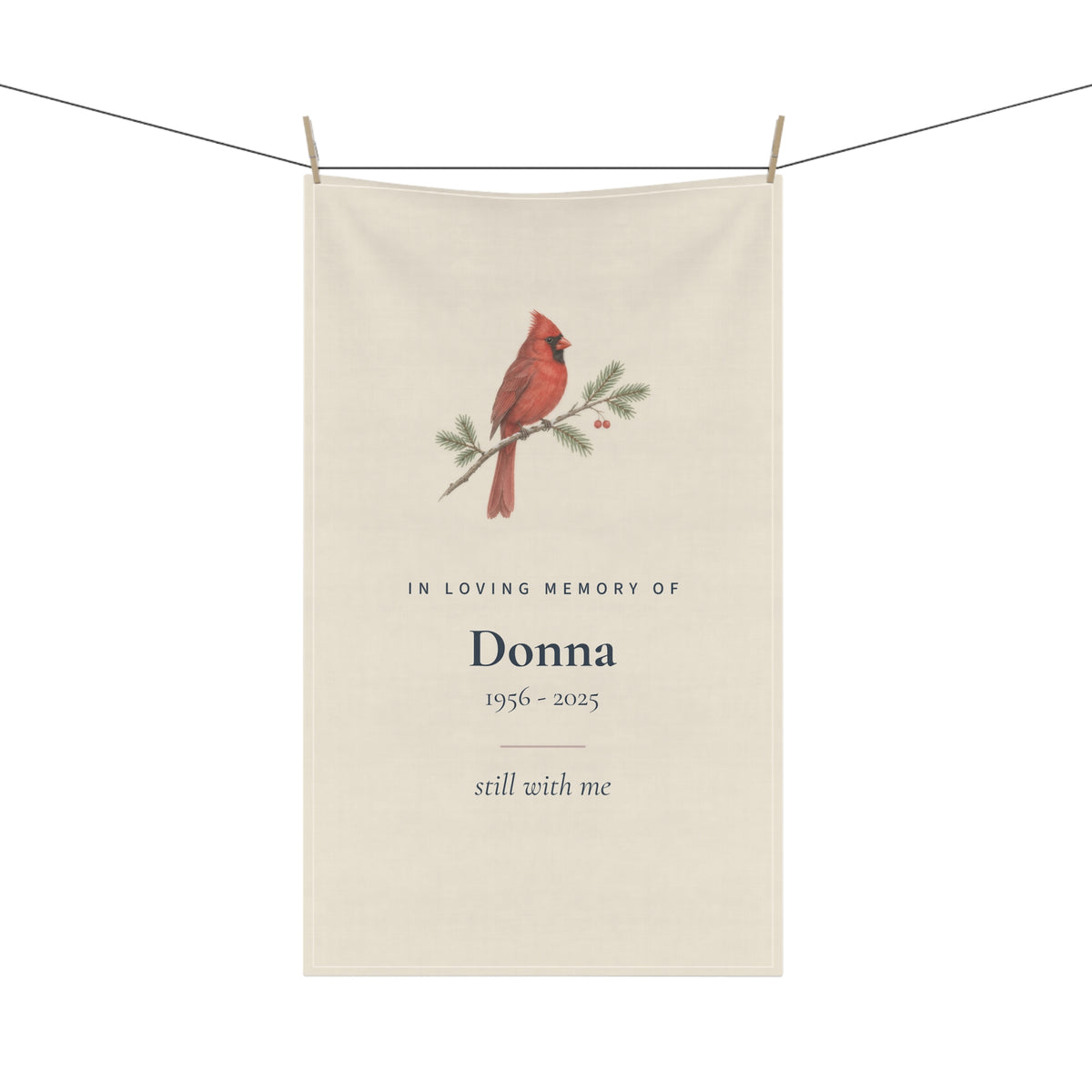 Cardinal memorial tea towel for Donna hanging on a line with wooden pegs