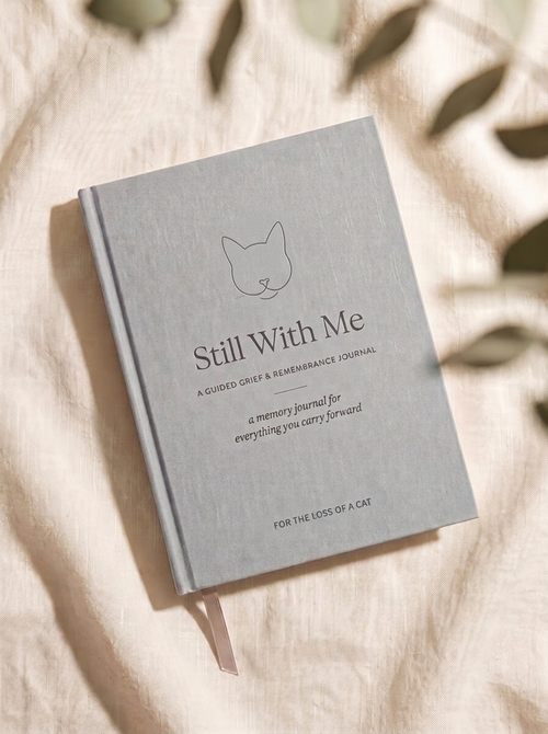 Still With Me — For the Loss of a Cat. Silver-grey linen memorial journal with a fine-line cat emblem.