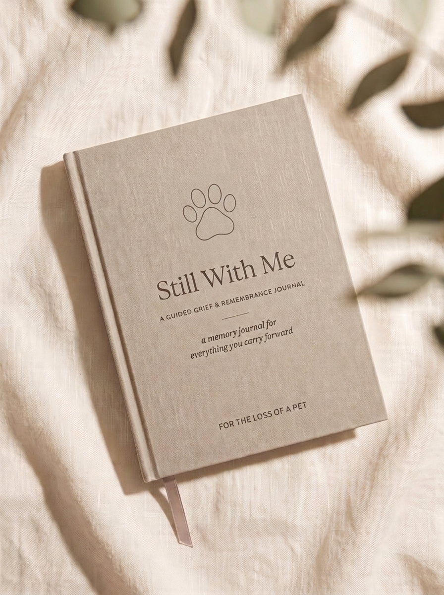 Still With Me — For the Loss of a Pet. Warm greige linen memorial journal with a fine-line paw emblem.