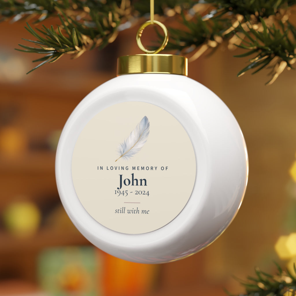 Feather memorial Christmas ball for John hanging on a lit Christmas tree