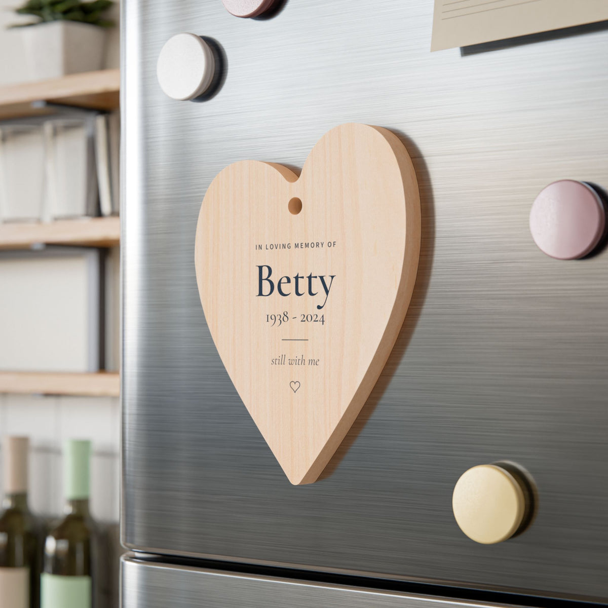 Personalized wooden heart memorial ornament with the name Betty resting on a fridge with its magnetic back